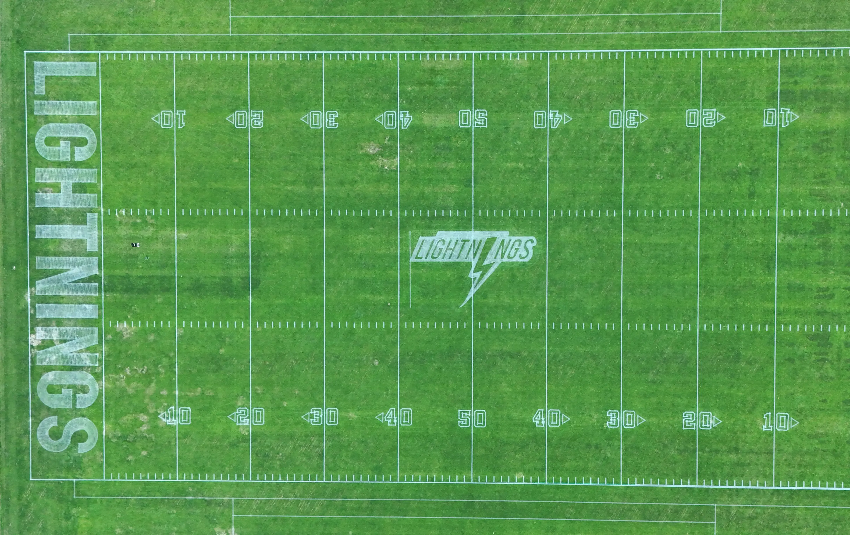 Aerial view of a club logo painted on turf by a PaintMaster line-marking robot