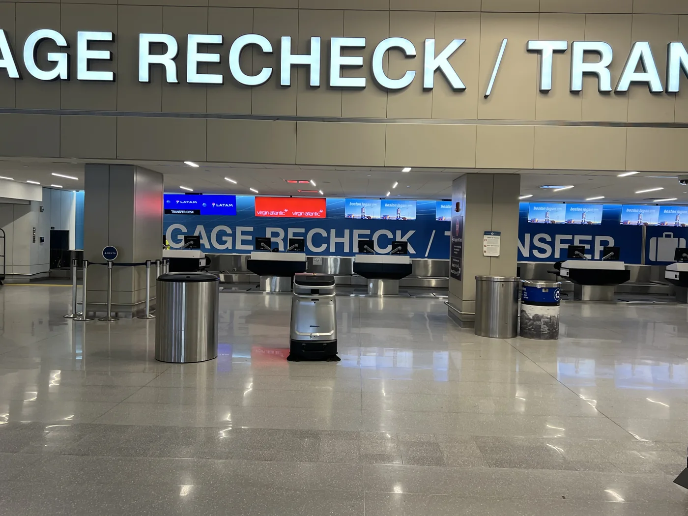 An autonomous SP50 spot-cleaning vacuum sweeper working an airport terminal concourse